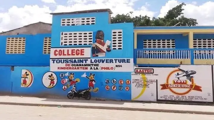 La façade bleue peinte du Collège Toussaint Louverture de Ouanaminthe, son nom en grandes lettres.