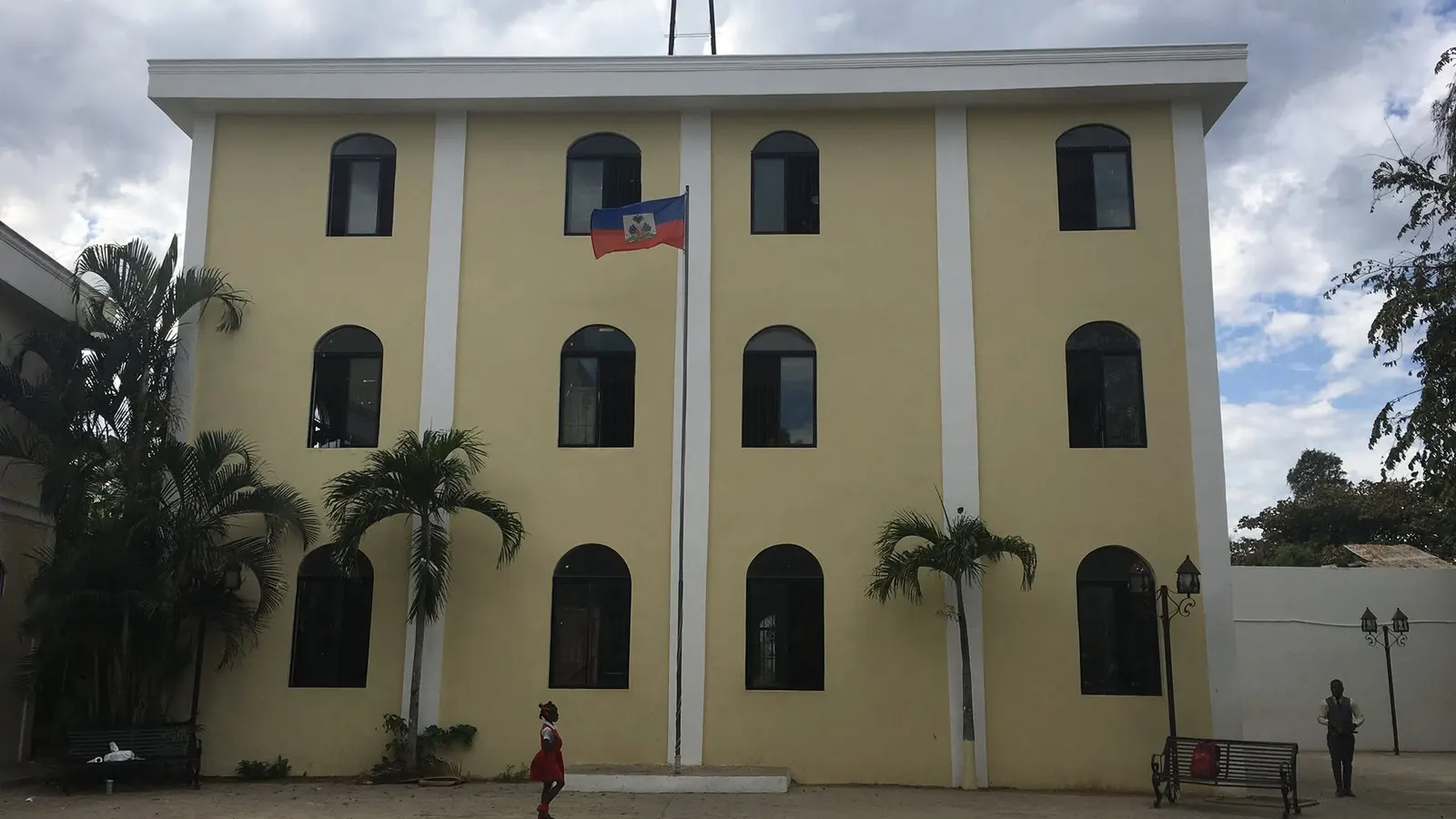 Le bâtiment jaune à trois étages d'Espoir Pour Haïti, drapeau haïtien devant la façade.