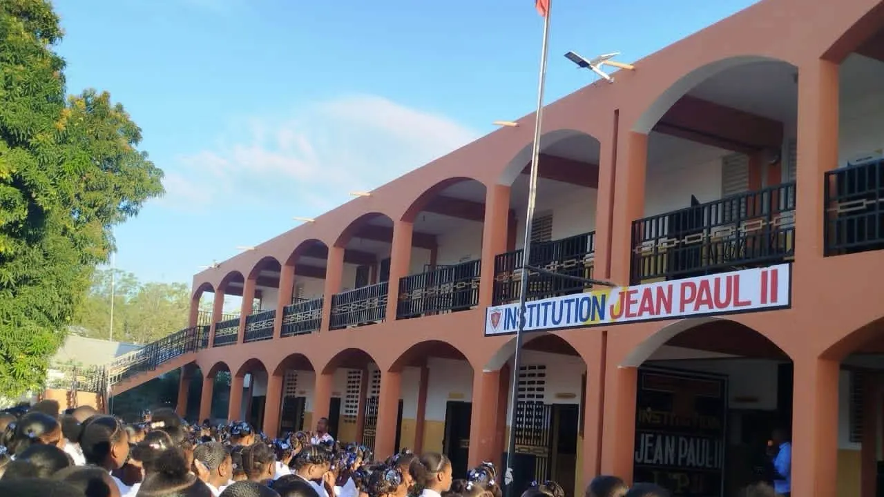Les arcades orange de l'Institution Jean Paul II, les élèves rassemblés au pied du bâtiment.